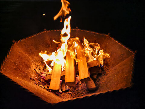 Night photo of a bonfire in an iron fire bowl. Photography of flame of burning wood on black background.