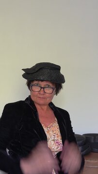 Person places a hat on her head and smiles softly. vertical video.
