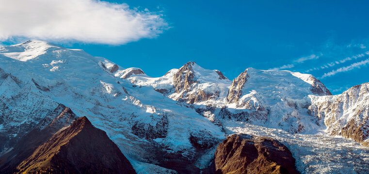 View of the Mont Blanc massif with snow-covered peaks, glaciers, and rocky slopes under a clear blue sky in Chamonix, Auvergne-Rhone-Alpes, France.