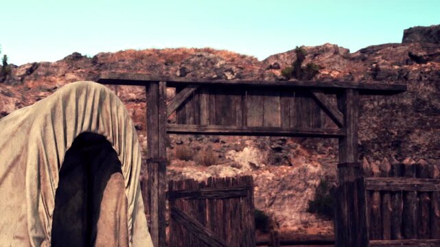 A figure stands near an old wooden structure in a desert region. The landscape includes rocky hills and dry vegetation. This scene captures a moment at midday.