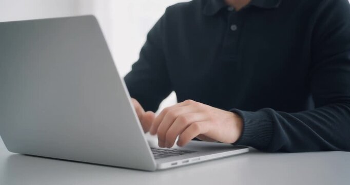 Professional man typing on modern silver laptop for remote business tasks