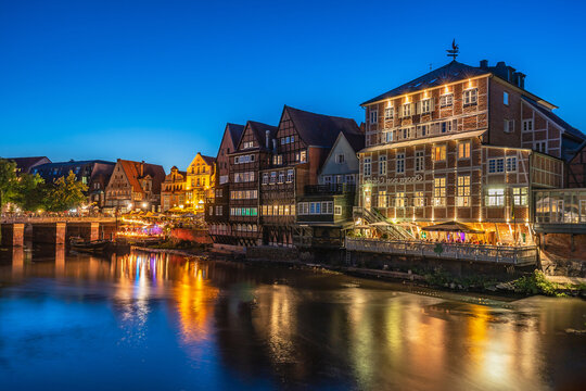 View of half-timbered buildings along the Ilmenau river at night in Luneburg, Germany.