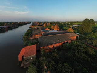 Naklejka premium Aerial panoramic view of Mang Thit pottery village with traditional red brick kilns along the river in Vinh Long, Vietnam.