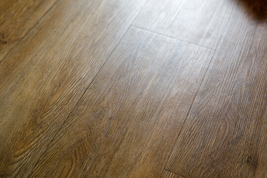Close-up of warm brown laminate wood flooring with natural grain, ideal for interior design concepts