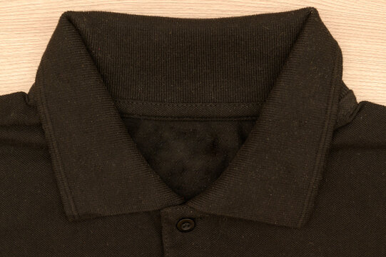 Black men's button-down collar sweater on a wooden background. Top view.