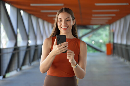 Brazilian business woman walking on footbridge and watching her mobile phone in Sao Paulo, Brazil