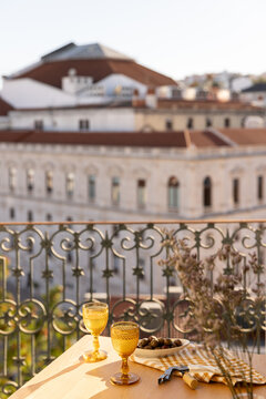 garnished olives in ceramic bowl on linen napkin with gold wine glass and balcony with city views in the background
