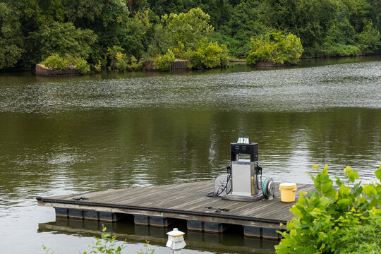 View of a floating fuel dock with a pump on a calm river surrounded by lush green trees in Henrico, Virginia, United States.