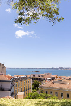 wide landscape shot of Lisbon, Portugal with orange tiled roofs looking towards Tagus River on a sunny clear day
