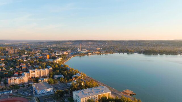 Russia, Votkinsk. Embankment with a dam and factories. Votkinsk is a city in the Udmurt Republic. Sunset time. Drone footage