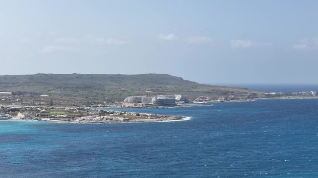 coral lagoon coastline turquoise cove curved resort hotel complex mellieha malta headland cliffs mediterranean sea aerial establishing shot red tower distant coastal development marfa peninsula