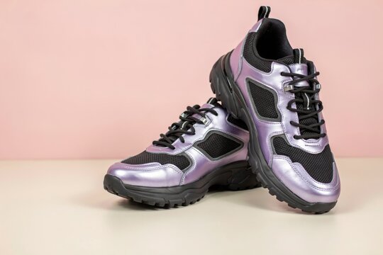 Pair of metallic purple and black chunky sneakers on a twotone background