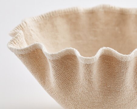 Close-up of a beige, textured fabric bowl with scalloped edges.
