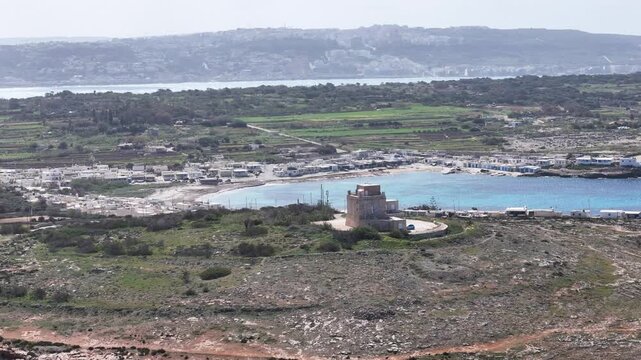 star shaped coastal watchtower fortified headland overlooking turquoise cove sandy beach mellieha malta aerial view distant coastline marfa peninsula mediterranean drone footage coral lagoon sea view