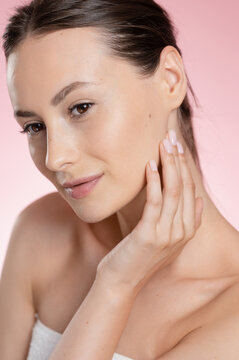 Young woman with clear skin gently touching her face with her hand