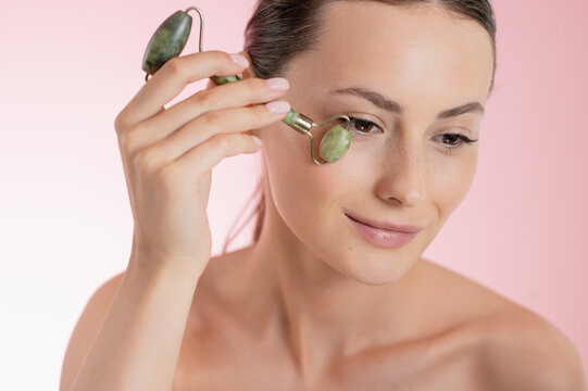 Woman using a jade roller on her face for skincare and beauty treatments