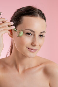 Woman using a jade roller for facial massage and skincare routine