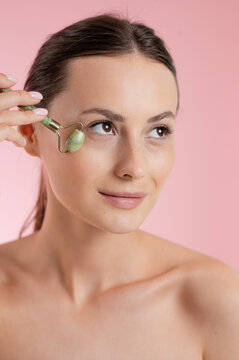 Woman using a jade roller for facial massage and skincare routine
