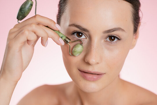 Woman using a jade roller on her face for skincare and beauty treatments