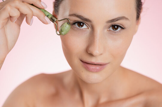 Woman using a jade roller for facial massage and skincare routine