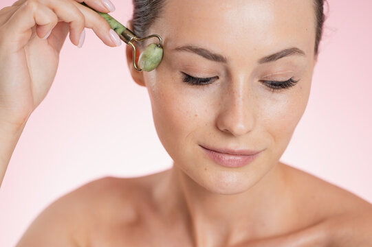 Woman gently massaging her face with a jade roller for skincare and beauty