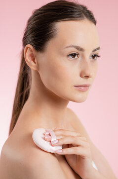 Young woman applying powder with a puff on her shoulder