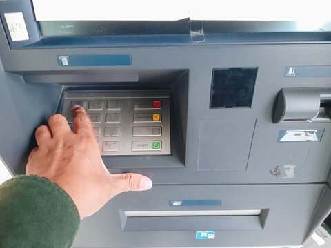 Human hand inserting bank card into atm for cash withdrawal