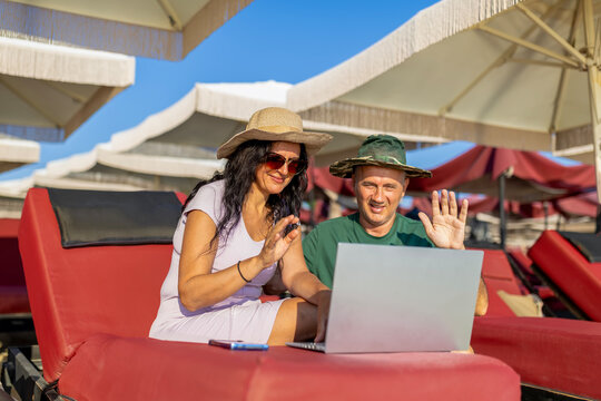 Couple enjoying beach vacation video calling on laptop