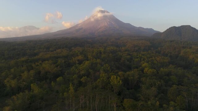 Aerial view of Mount Merapi volcano rising above lush tropical forests in the morning light in Kecamatan Turi, Daerah Istimewa Yogya, Indonesia.