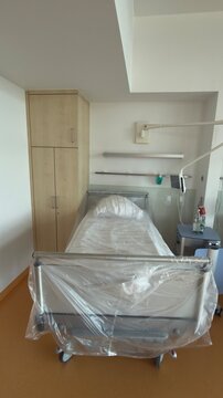 Frisch vorbereitetes Patientenbett mit Schutzfolie in einem Krankenhauszimmer. Hygienisch hergerichteter Schlafplatz f&uuml;r die Aufnahme eines neuen Patienten.