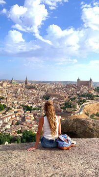 woman sitting cross legged overlooking toledo cityscape with cathedral and historic skyline spain, vertical video
