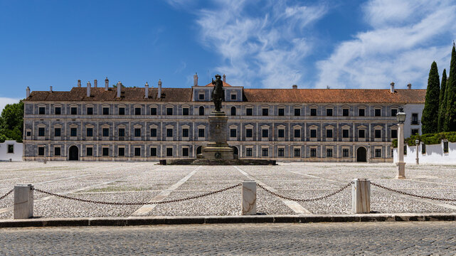 View of the Ducal Palace of Vila Vicosa with its marble facade and equestrian statue in the foreground, set against a clear blue sky in Vila Vicosa, Distrito de Evora, Portugal.