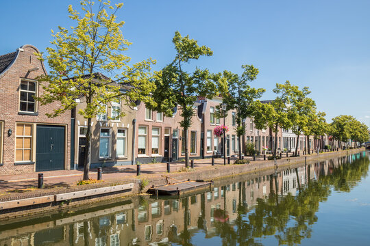 Historic brick houses align beside a calm tree-lined canal in Meppel, Netherlands