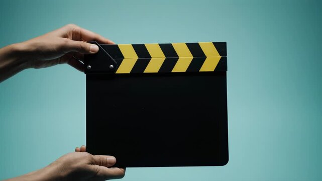 Hand holding black and yellow clapperboard in motion