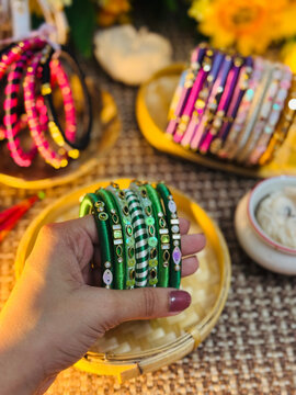 Woman hand holding green bangles with traditional patterns