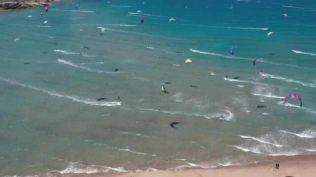 14 June 2026 Prasonisiou, Rodos: Dynamic aerial drone footage of windsurfers riding the waves at Prasonisi Beach in Rhodes, Greece. Bird's-eye view of windsurfing action, turquoise Mediterranean water