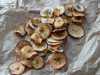 Fototapeta premium Dried apple slices are arranged diagonally on light-coloured craft paper.