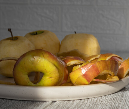 A plate with three yellow, peeled apples and an apple core against a white background.