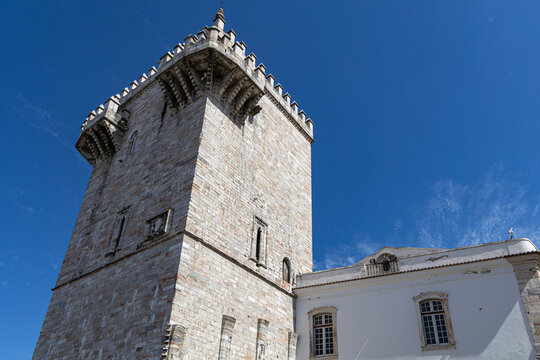 View of the historic marble Torre das Tres Coroas with its crenellated battlements against a clear blue sky in Estremoz, Evora District, Portugal.