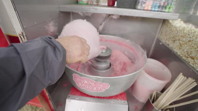 Hombre preparando algod&oacute;n de az&uacute;car, elaboraci&oacute;n de dulce tradicional en feria o puesto gastron&oacute;mico
