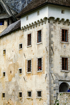 View of the historic stone walls and windows of Bled Castle with a person in a red hat looking out in Bled, Radovljica, Slovenia.