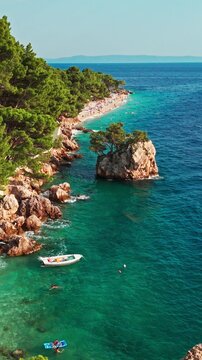 Vertical aerial drone reveal shot flying backwards over Brela Rock in Croatia