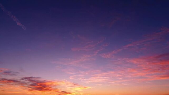 Dramatic sunset sky with a long airplane contrail and soft pink and orange clouds