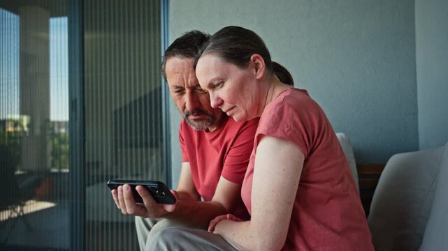 Smiling man and woman watching something amusing on mobile phone, digital entertainment and positive relationship concept, 4K