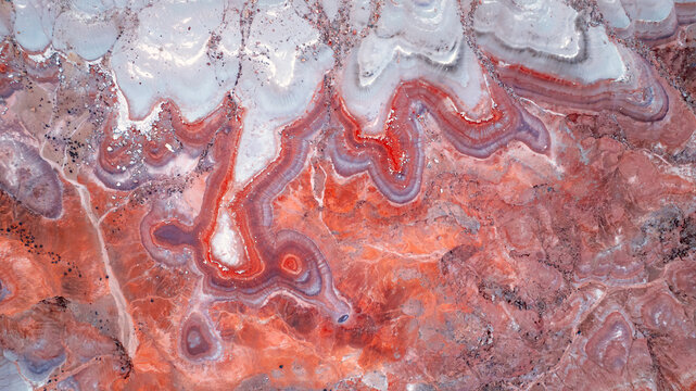 Aerial view of the colorful Bentonite Hills with distinct red, purple, and white clay layers and eroded desert terrain in Wayne County, Utah, United States.