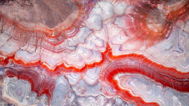 Aerial view of the colorful, banded clay formations of the Bentonite Hills, featuring vibrant red, white, and purple layers in the desert landscape of Wayne County, Utah, United States.