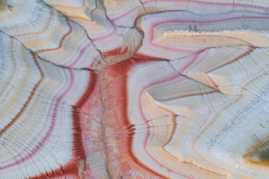 Aerial view of the unique layered rock formations of Kyzyl Kup, also known as Tiramisu, with vibrant red, white, and tan geological stripes in Karakiya District, Mangystau Region, Kazakhstan.