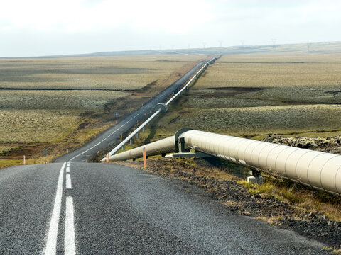 Aerial view of the Nesjavellir Geothermal Power Station pipeline running parallel to a winding asphalt road through the mossy volcanic landscape of Selfoss, Grimsnes- og Grafning, Iceland.