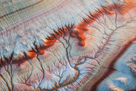 Aerial view of colorful, layered geological formations of Kyzyl Kup, with intricate erosion patterns and vibrant clay textures in Karakiya District, Mangystau Region, Kazakhstan.