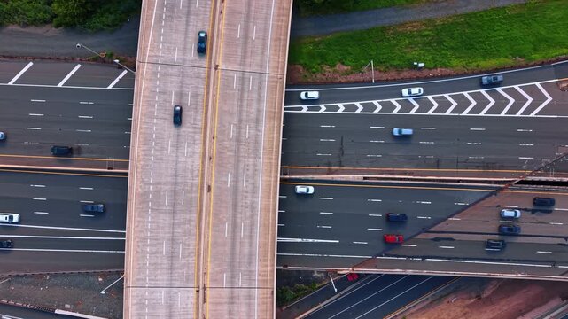 Overhead top down perspective of multi lane highway lanes, New Jersey, USA. Bird eye drone view of cars driving across asphalt road marking and green grass.
